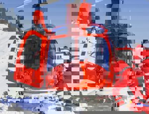 Rescue helicopter landed on a snowy mountainside with two emergency responders