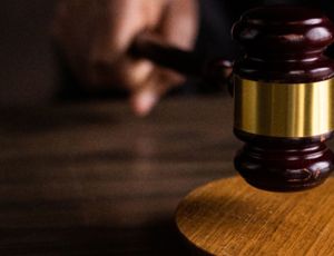 Judge’s gavel striking a wooden sound block in a courtroom setting