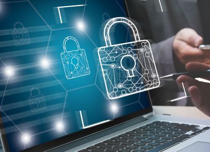 Laptop displaying digital padlock icons representing cybersecurity, with people using a tablet and stylus in the background