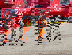 Air ambulance crew in orange flight suits walking away from a red helicopter during an emergency response