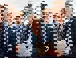 Group of students gathered around another person holding a tablet during a lab activity