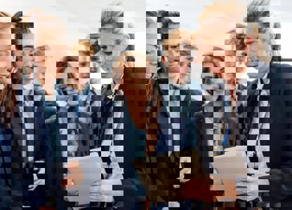 Group of students gathered around another person holding a tablet during a lab activity