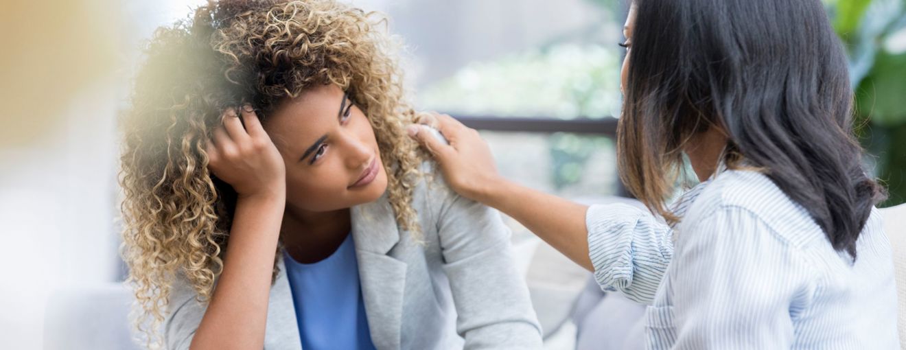 Person comforting someone who is distressed, with a hand placed supportively on their shoulder