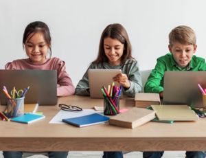School children in a classroom using digital devices