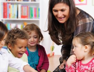 Teacher interacting with a small group of young children in a colourful classroom setting