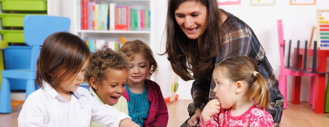 Teacher interacting with a small group of young children in a colourful classroom setting